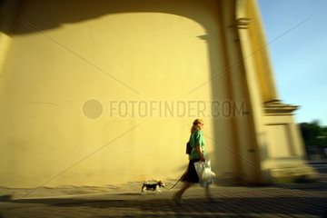 Frau mit Hund vor gelber Wand