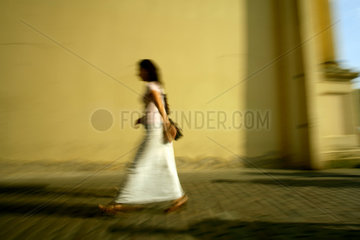 Frau im weissen Kleid vor gelber Wand