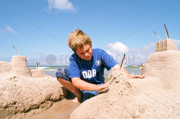 Junge baut am Strand eine Burg an der Ostsee