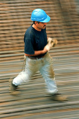 Bauarbeiter laeuft auf einem Stahlgitter