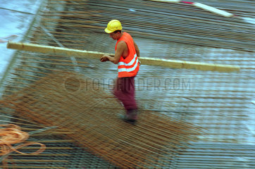 Bauarbeiter traegt einen Holzbalken