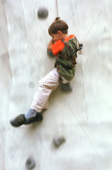 Junge haengt am Seil einer Kletterwand