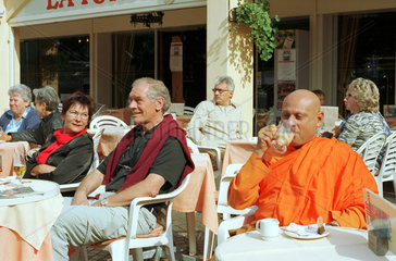Buddistischer Moench und Touristen in einem Cafe
