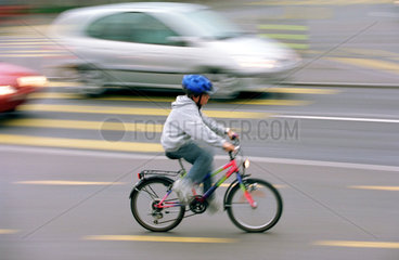 Kind mit Helm auf dem Fahrrad im Stadtverkehr