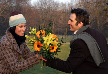 Mann gibt Frau einen Blumenstrauss