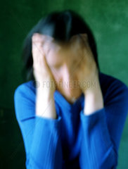 Deprimiert wirkende Frau reibt Haende an den Kopf
