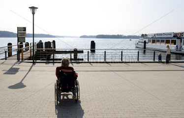 Bad Saarow  eine aeltere Frau im Rollstuhl geniesst den Ausblick auf den Scharmuetzelsee