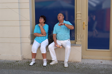 Rentnerpaar sitzt vor leerem Geschaeft in Brandenburg