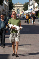 Mann traegt mueden Hund in Potsdam