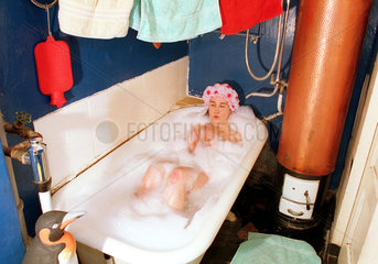 Frau sitzt mit einer Duschhaube in einer Badewanne