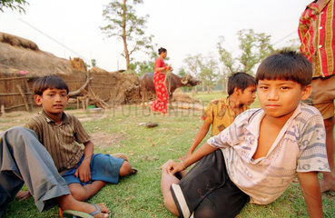 Jungen sitzen auf einer Wiese eines Dorfes in Nepal