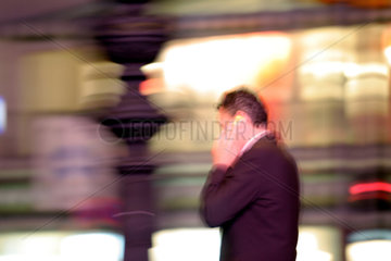 Mann telefoniert im abendlichen Stadtverkehr in Berlin
