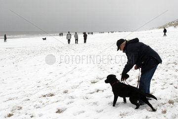 Spaziergaenger und Hund im Schnee auf Sylt