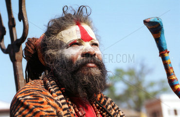 Ein Sadhu mit Asche im Gesicht und Dreizack in Nepal