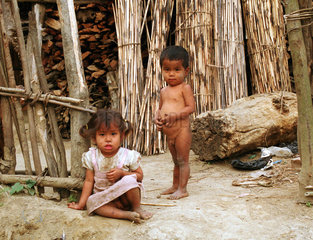 Maedchen und Junge vor einer Holzhuette in Nepal