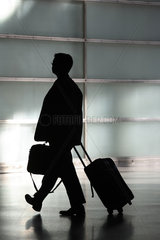 Silhouette eines Mannes mit Aktentasche und Rollkoffer