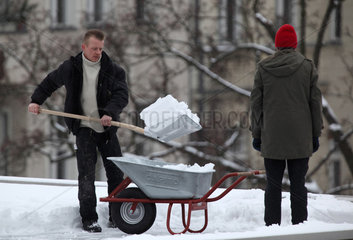 Berlin  Deutschland  Mann schippt Schnee von einem Flachdach