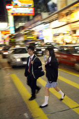 Schueler ueberqueren eine Strasse im Stadtteil Kowloon in Hongkong