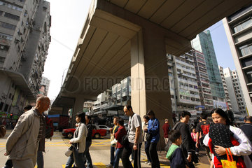 Menschen ueberqueren eine Strasse im Stadtteil Kowloon in Hongkong