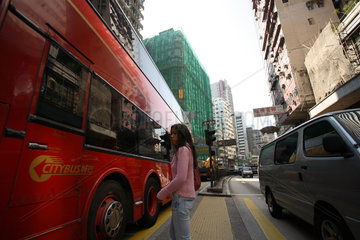 Frau wartet auf einer Strasse im Stadtteil Kowloon in Hongkong