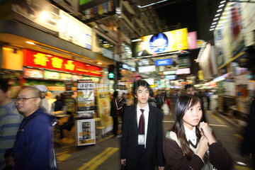 Junge Menschen in einer Geschaeftsstrasse im Stadtteil Kowloon in Hongkong