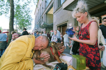Frau gibt einem Mann mit Hund etwas Geld in Berlin