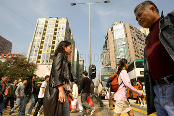 Menschen ueberqueren eine Strasse im Stadtteil Kowloon in Hongkong