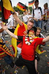 Berlin  Fussballfans WM 2006: Feiernde Maenner und deutsche Fahnen