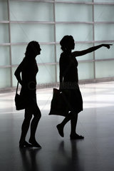 Silhouetten zweier junger Frauen  eine zeigt den Weg