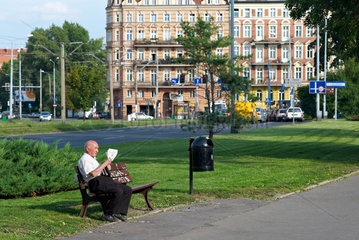 Breslau  Polen  ein alter Mann sitzt auf einer Parkbank und liest Zeitung