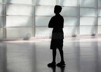 Silhouette eines Jungen mit verschraenkten Armen