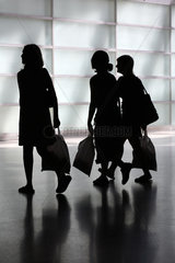 Silhouetten von drei jungen Frauen mit Taschen