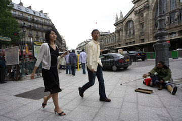 Elegantes Paar und um Spenden bittender Mann in Paris