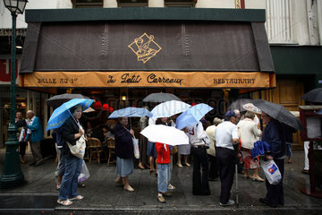 Touristen mit Regenschirmen vor einem Restaurant in Paris