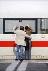 Paar winkt am Fenster eines Zuges zum Abschied