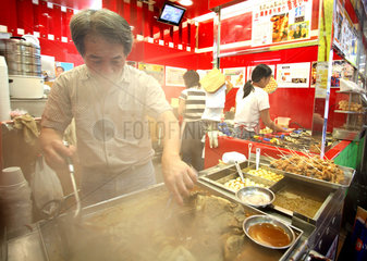 Hong Kong  Mann braet Fleisch in einem Imbiss
