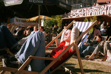 Sich sonnende Frau im Liegestuhl eines Cafes in Berlin