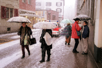 Menschen mit Regenschirmen bei Schneegestoeber