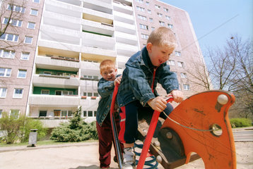 Zwei Brueder spielen vor einem Hochhaus in Berlin