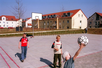 Kinder spielen Ball in einer Neubausiedlung in Berlin