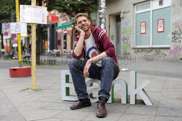 Berlin  Deutschland  ein Mann sitz an einer Bushaltestelle auf dem Schriftzug Bank