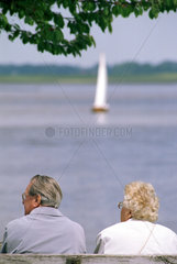 Rentnerpaar schaut auf Wasser mit Schiff