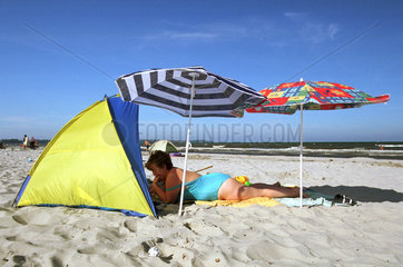 Frau am Strand mit Sonnenschutz und Sonnenschirmen