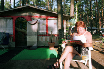 Eine Frau liest vor ihrem Wohnwagen in Berlin