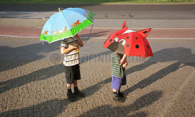 Kinder mit Schirmen als Sonnenschutz