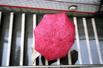 Frau unter Regenschirm laeuft die Treppe hinunter