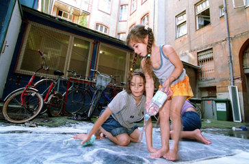 Familie waescht Teppich in einem Berliner Hinterhof