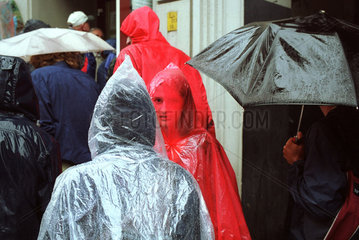 Menschen in Regenkleidung und mit Schirmen in Berlin