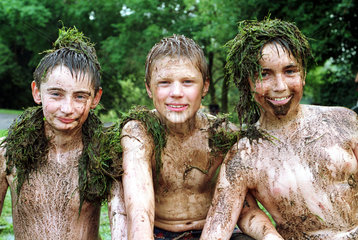 Drei Jungen mit Schlamm und Gras bedeckt
