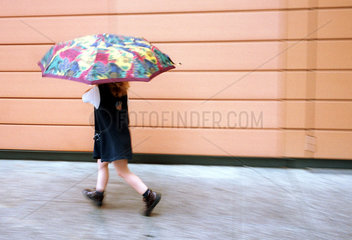Maedchen rennt mit dem Regenschirm